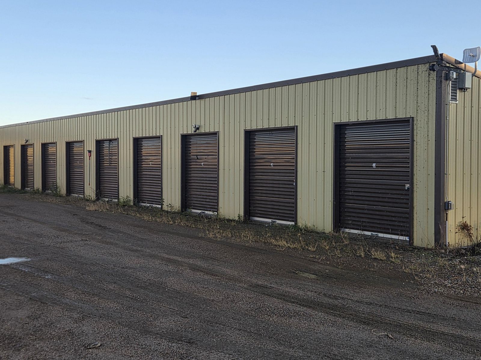 Storage unit building with dark roll-up doors and a camera mounted on the wall